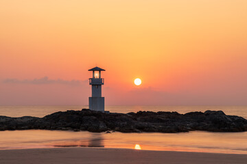 Khao Lak light beacon or lighthouse for navigation on rock near beach during sunset, famous travel...