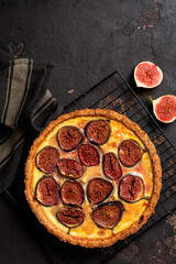 Homemade quiche tart with figs, cream cheese and honey on dark brown background. Vintage style. Top view