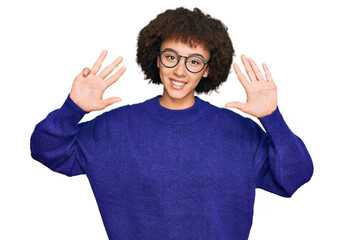 Young hispanic girl wearing casual winter sweater and glasses showing and pointing up with fingers number nine while smiling confident and happy.