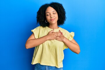 Young african american girl wearing casual clothes smiling with hands on chest with closed eyes and grateful gesture on face. health concept.