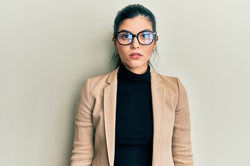 Young hispanic woman wearing business style and glasses with serious expression on face. simple and natural looking at the camera.