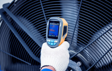 Technician uses a thermal imaging infrared thermometer to check the condensing unit heat exchanger.