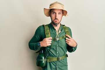 Handsome man with beard wearing explorer hat and backpack depressed and worry for distress, crying angry and afraid. sad expression.