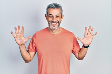 Handsome middle age man with grey hair wearing casual t shirt showing and pointing up with fingers number ten while smiling confident and happy.