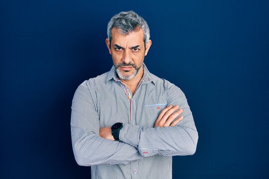 Handsome middle age man with grey hair wearing business shirt skeptic and nervous, disapproving expression on face with crossed arms. negative person.