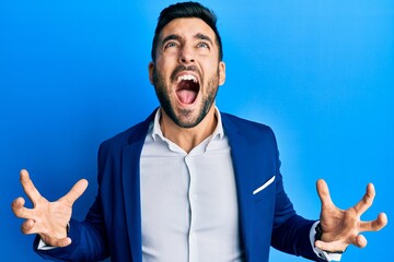 Young hispanic businessman wearing business jacket crazy and mad shouting and yelling with...