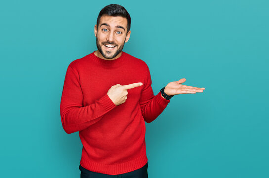Young hispanic man wearing casual clothes amazed and smiling to the camera while presenting with hand and pointing with finger.