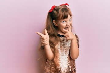 Little caucasian girl kid wearing festive sequins dress pointing fingers to camera with happy and funny face. good energy and vibes.