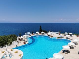 Fototapeta na wymiar Luxurious pool with blue water and sea views. Sun loungers and umbrellas near the pool in the resort of Kusadasi, Turkey.