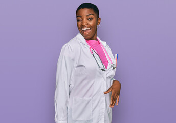 Young african american woman wearing doctor uniform and stethoscope winking looking at the camera...