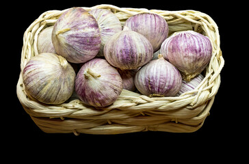 Pile of fresh garlic in a wooden basket, all is on black background
