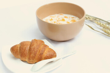 Breakfast with cereal in milk and fresh croissant