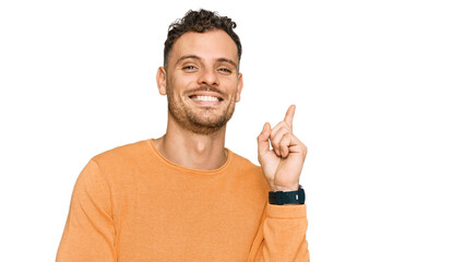 Fototapeta premium Young hispanic man wearing casual clothes with a big smile on face, pointing with hand and finger to the side looking at the camera.