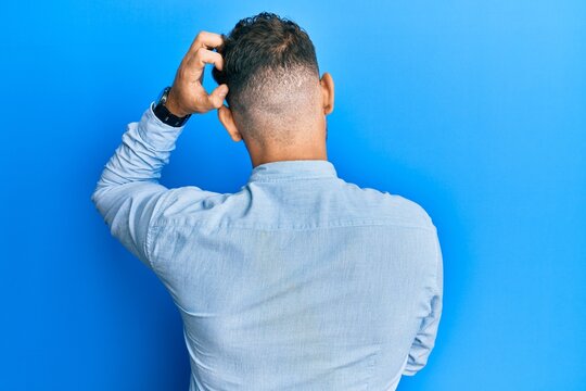 Young hispanic man wearing casual clothes and glasses backwards thinking about doubt with hand on head