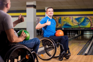Two young disabled men in wheelchairs playing bowling in the club