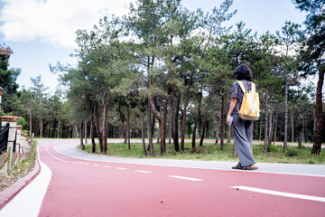 A woman walking in the urban forest. Woman with bag walking. Woman walking on the footpath. A woman walking for health. Selective focus.