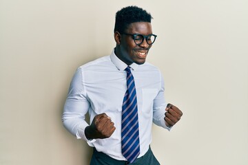 Handsome black man wearing glasses business shirt and tie excited for success with arms raised and eyes closed celebrating victory smiling. winner concept.