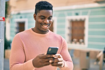 Young african american man smiling happy using smartphone at the city.