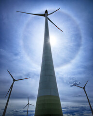 The Halo effect is an optical phenomenon in the Earth's atmosphere that is observed around the Sun's disc. It is a rainbow-colored ring that is visible around the sun. Gaj Olawski wind farm. - obrazy, fototapety, plakaty