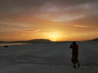 Fototapeta na wymiar silhouette of person walking on the beach at sunrise