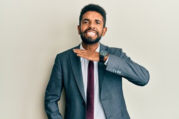 Handsome hispanic man with beard wearing business suit and tie cutting throat with hand as knife, threaten aggression with furious violence