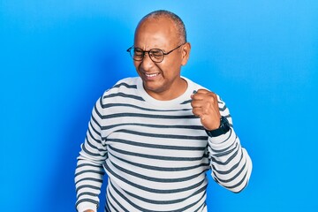 Naklejka premium Middle age latin man wearing casual clothes and glasses celebrating surprised and amazed for success with arms raised and eyes closed. winner concept.
