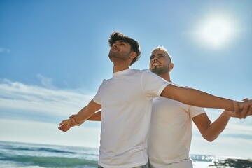 Young gay couple smiling happy breathing at the beach.