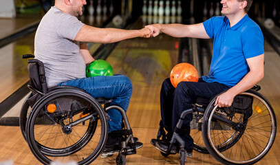 Two young disabled men in wheelchairs playing bowling in the club