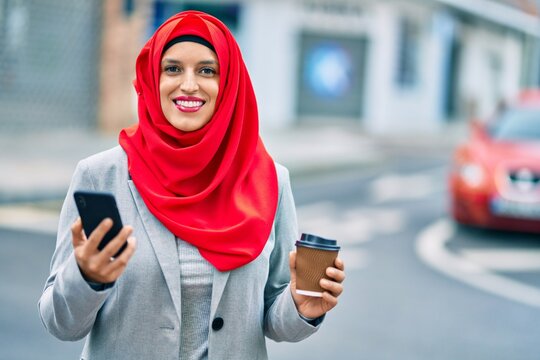 Young arab businesswoman using smartphone and drinking coffee at the city.