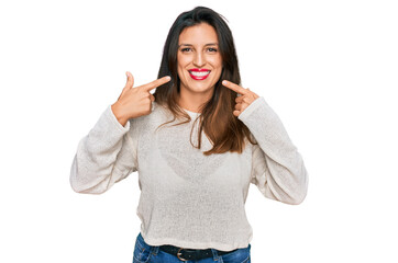 Obraz na płótnie Canvas Beautiful hispanic woman wearing casual sweater smiling cheerful showing and pointing with fingers teeth and mouth. dental health concept.