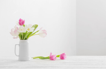 white and pink tulips in jug on white background