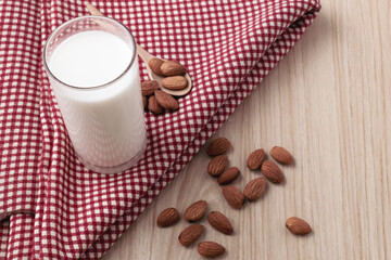 almond milk in glass and spoon with nuts are around on red cloth on wood background. selective focus.top view, top-down, flat lay.