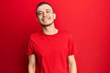 Hispanic young man wearing casual red t shirt with a happy and cool smile on face. lucky person.