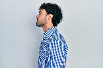 Young hispanic man wearing casual clothes looking to side, relax profile pose with natural face with confident smile.