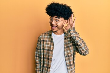Fototapeta na wymiar Young african american man with afro hair wearing casual clothes smiling with hand over ear listening and hearing to rumor or gossip. deafness concept.