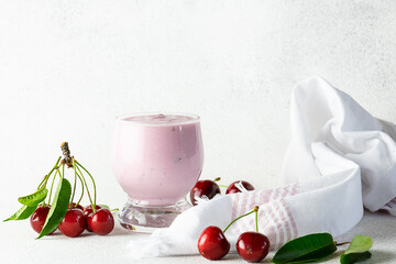 Homemade cherry yogurt in a glass with fresh cherries on white marble background with copy space for your design. Healthy food concept.