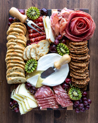 Top down view of a meat and cheese charcuterie board against a wooden background.