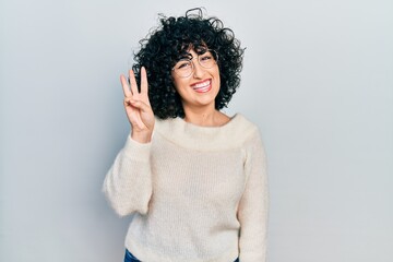 Young middle east woman wearing casual white tshirt showing and pointing up with fingers number three while smiling confident and happy.