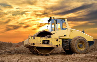 Soil Compactor for leveling ground for the foundation and on road construction. Road compaction equipment at construction site. Vibration single-cylinder road roller on amazing sunset background.
