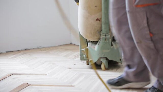 Repairman restoring parquet with a sanding machine.