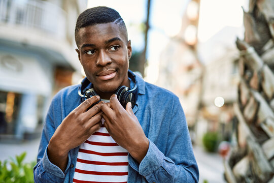 Young african american man with serious expression using headphones at the city.