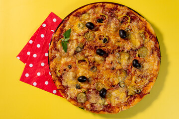 Pizza with vegetables lies on a red napkin on a bright yellow background. Space for the text. Top view.