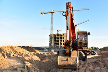 Bucket wheel excavator on earthmoving at construction site. Backhoe earthworks. Earthmoving heavy equipment for construction. Tower crane during the construction of a skyscraper. Building industry