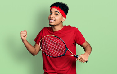 Young african american man wearing tennis player uniform screaming proud, celebrating victory and success very excited with raised arm