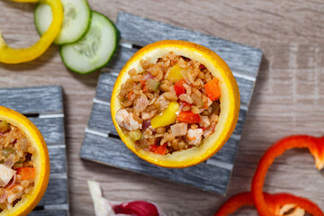 Fried bulgur with turkey meat and stewed vegetables served in cups made of orange peel. Exotic delicious dish, top view