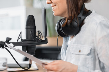 podcaster creates content, European woman records podcast with microphone and headphones, Caucasian...