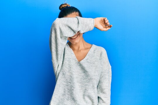 Young hispanic woman wearing casual clothes covering eyes with arm smiling cheerful and funny. blind concept.