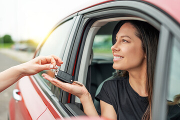 An attractive woman in a car gets the car keys. Rent or purchase of auto - concept.