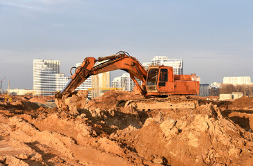 Excavator on earthmoving at construction site. Backhoe earthworks. Earthmoving heavy equipment for construction. Building industry.