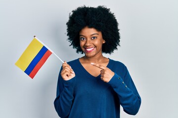 Young african american woman holding colombia flag smiling happy pointing with hand and finger